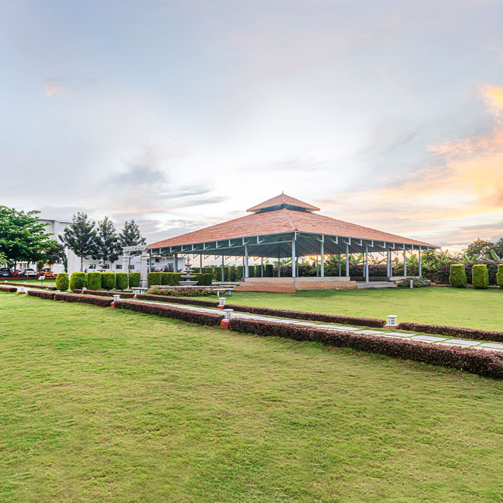 The canopied Aarunya hall on the lawn at sunset