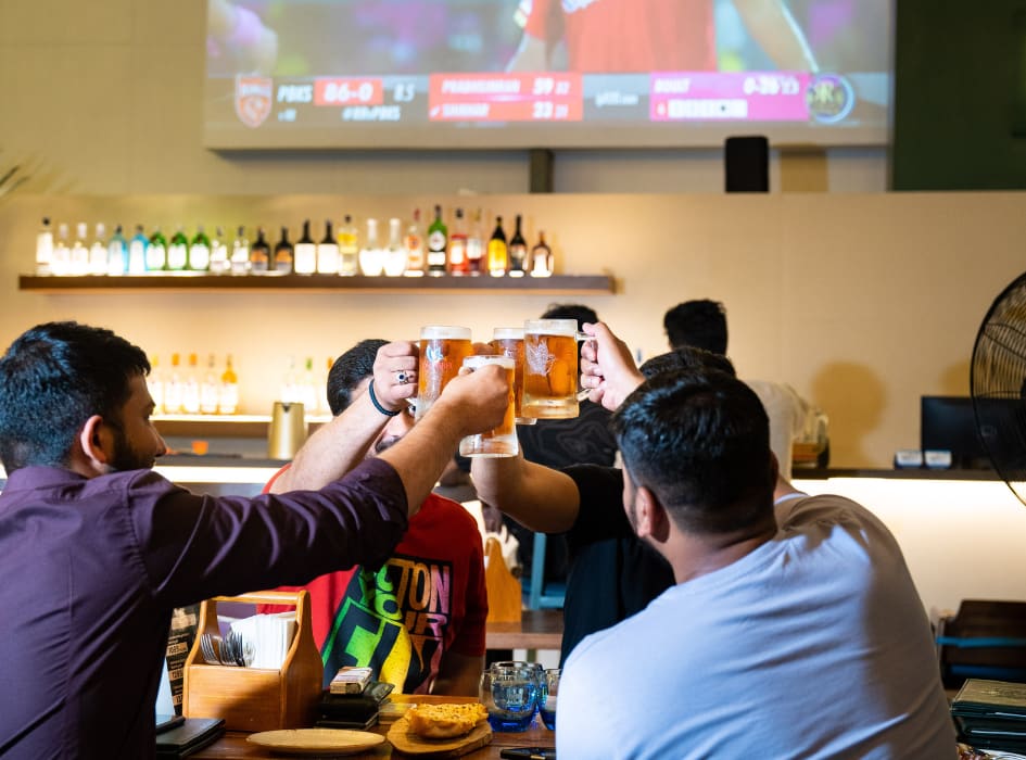 Friends raising glasses at the bar during a match screening