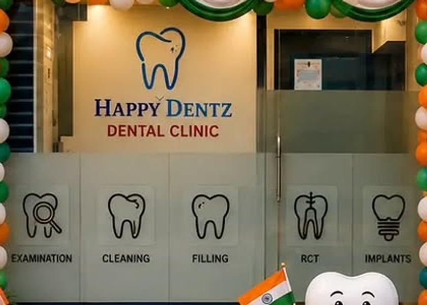 Inside the Happy Dentz entrance: the logo wall and the frosted door with Examination, Cleaning, Filling, RCT and Implants drawn on it