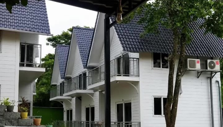 A row of white gabled cottages with balconies among the trees