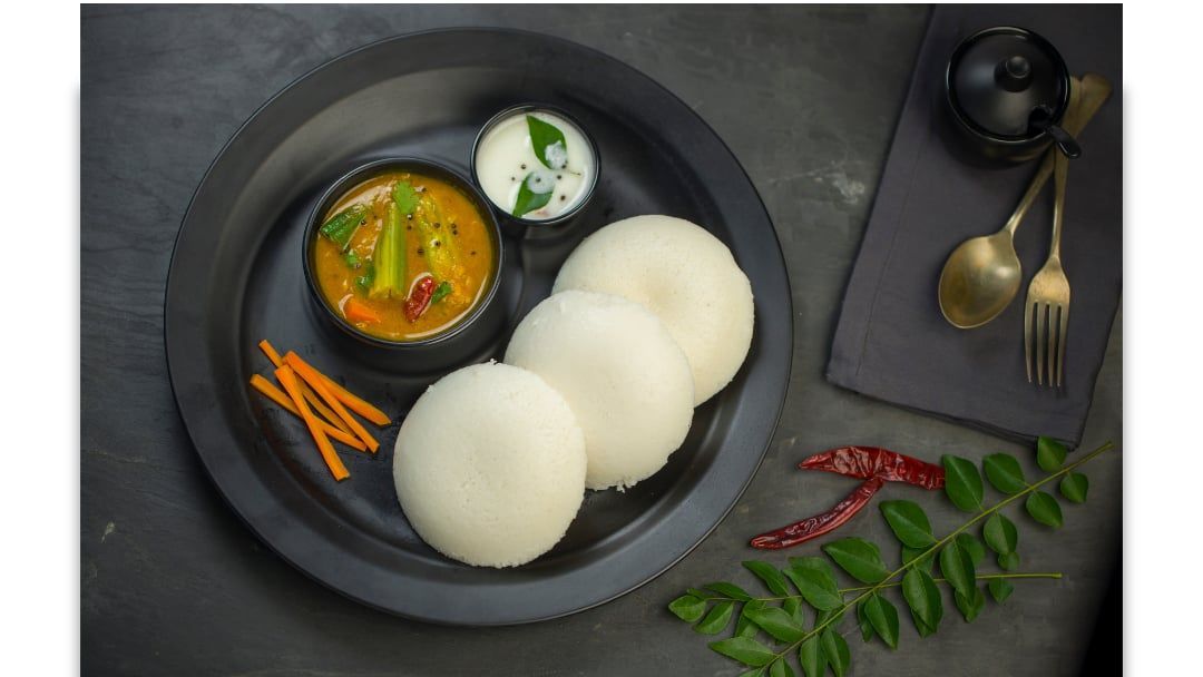 Idli with sambar and coconut chutney on a slate plate