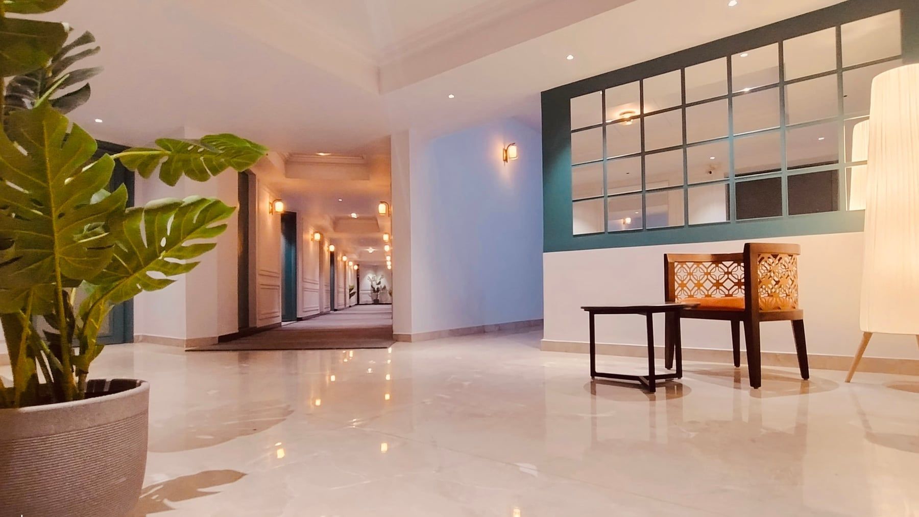 The Hans Hotel lobby — marble floors, a lattice chair and a monstera by the glass partition