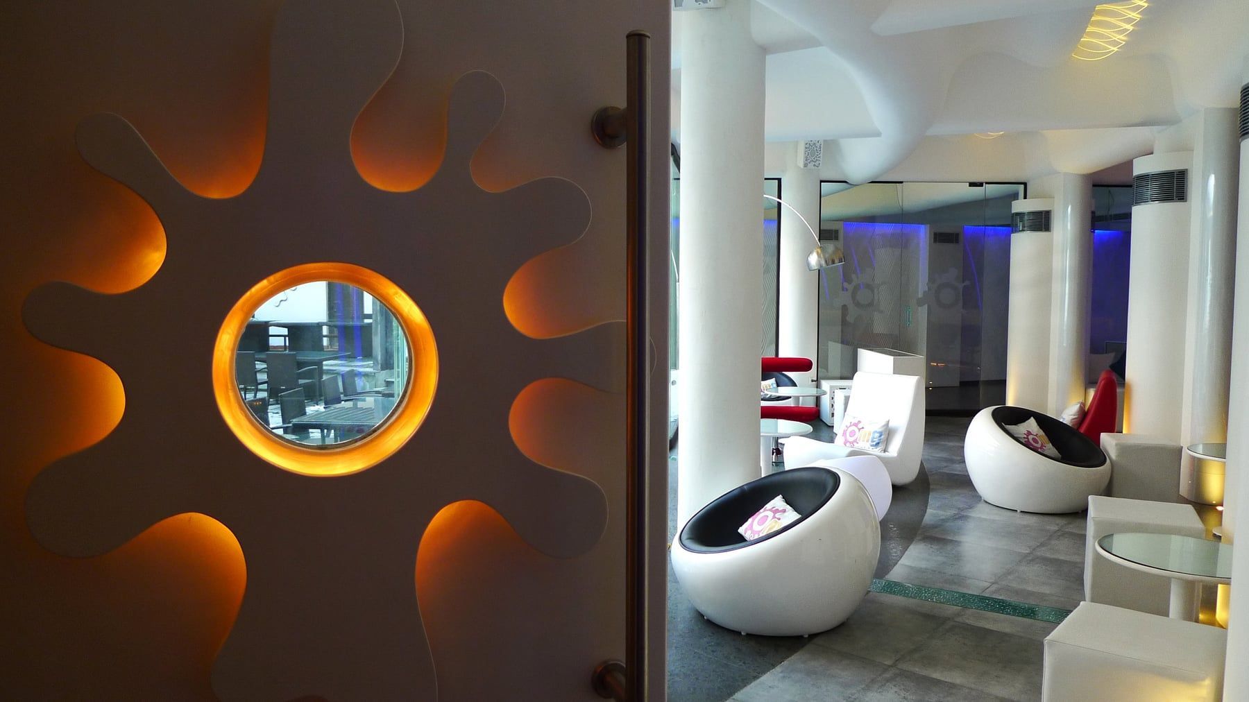 Lounge with a glowing sunburst wall and pod chairs