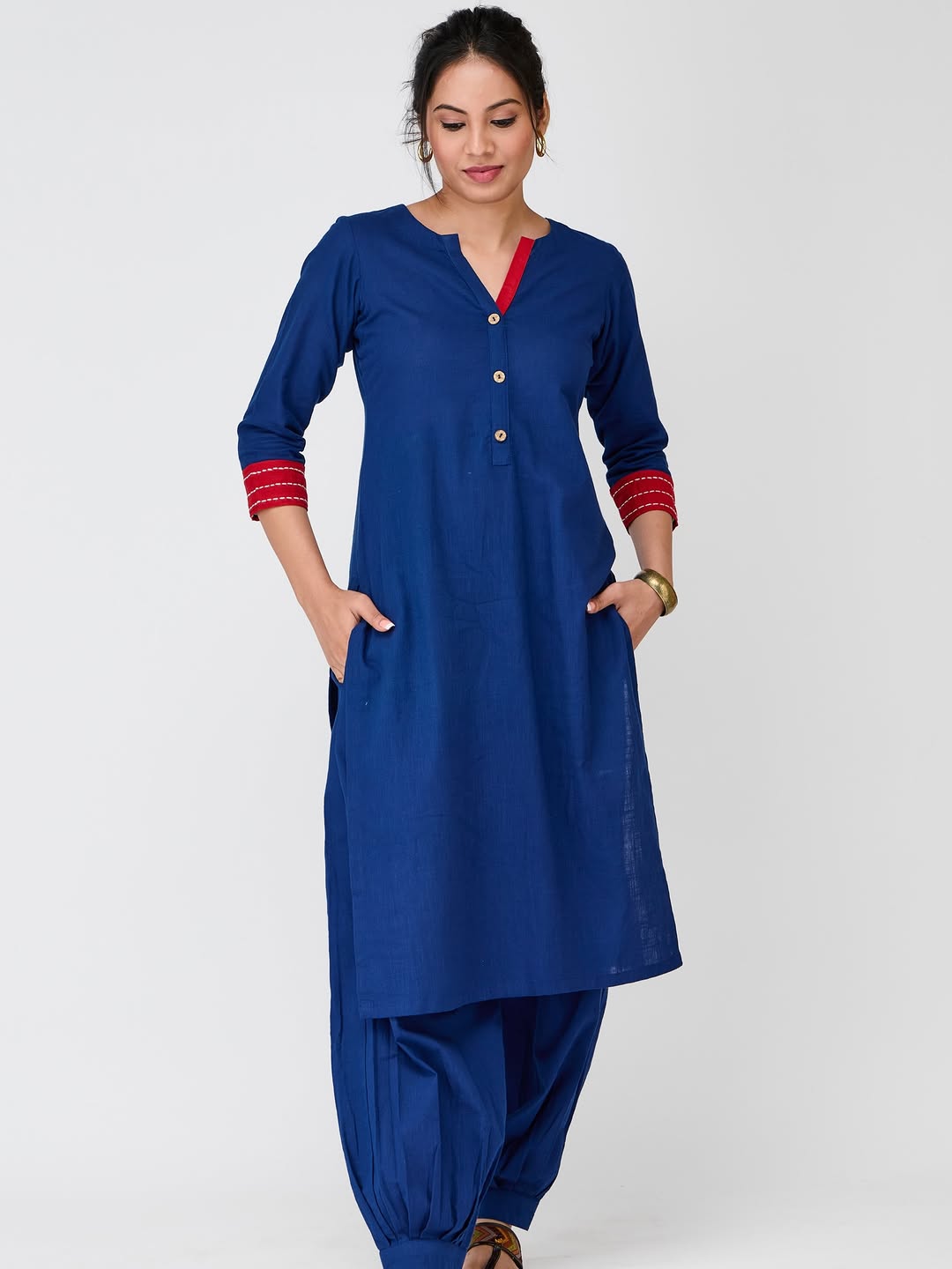 The indigo Neelambari kurta set with red cuffs, hands in its pockets