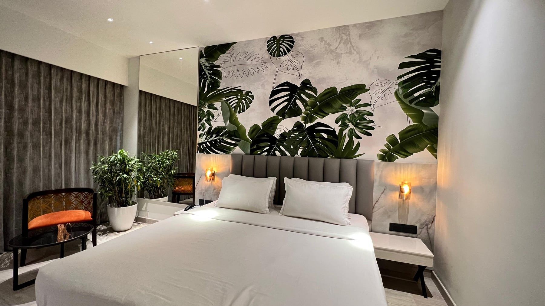 Deluxe room with a botanical mural behind a king bed