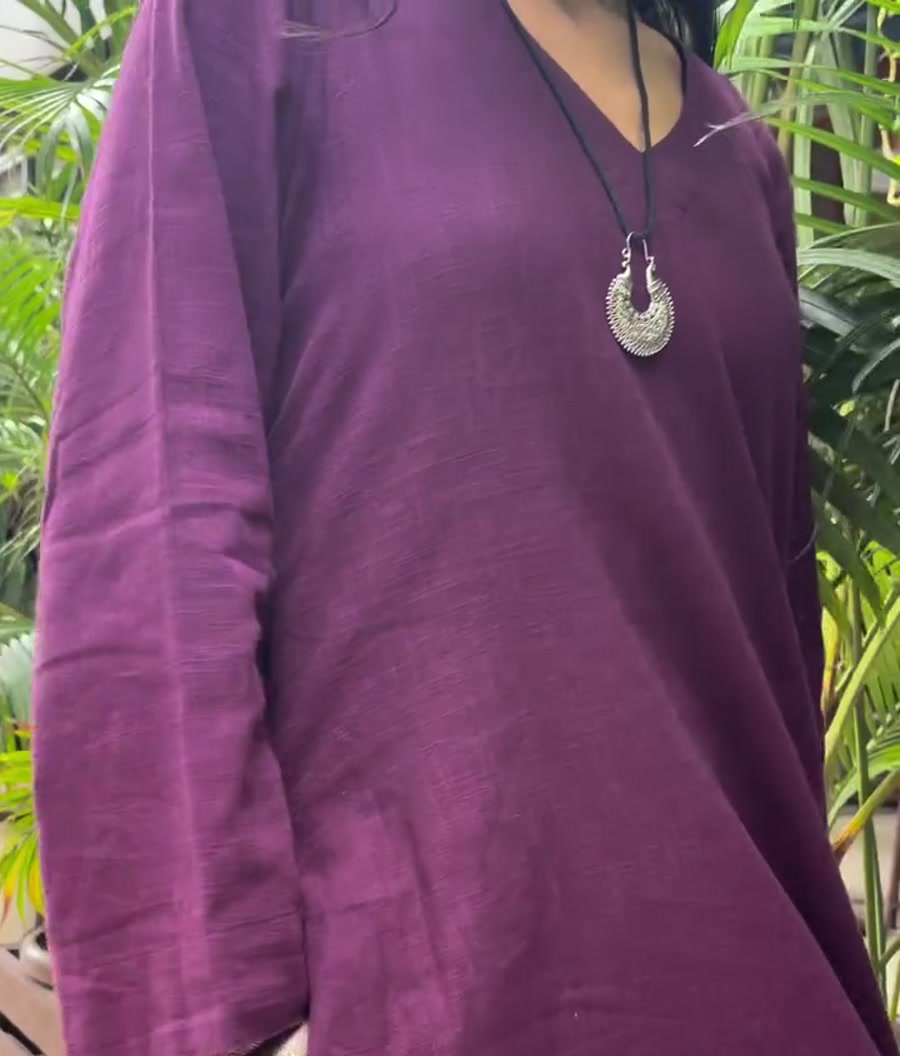 A smiling model in a plum kurta with a silver pendant