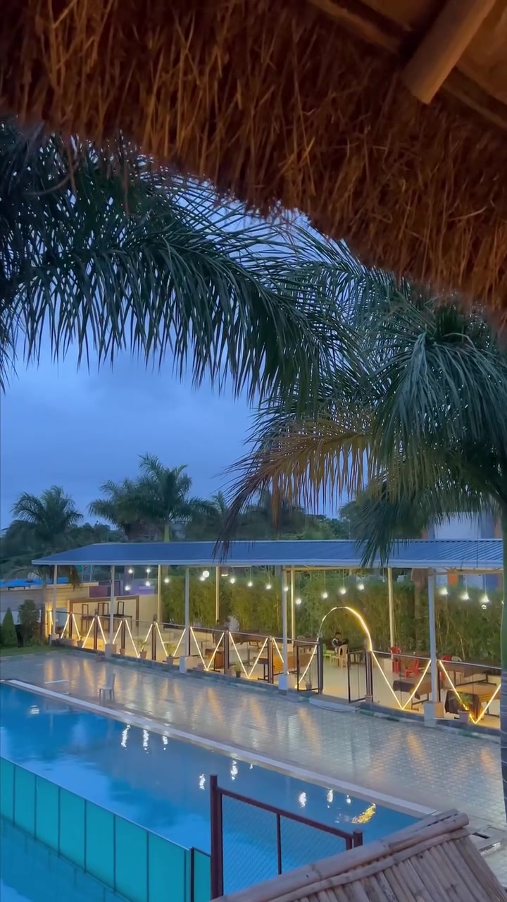 The same pool at dusk, lit blue, with lights strung along the far side