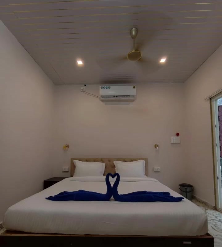 A cottage bedroom with a double bed, folded towels and air-conditioning