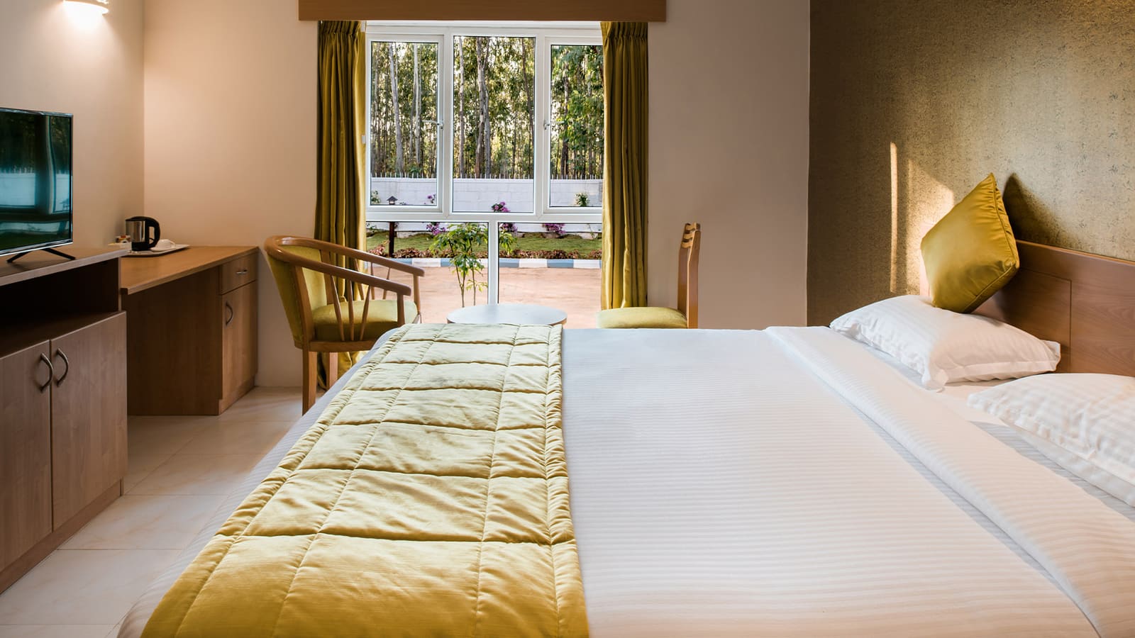 A garden-view room with twin beds and olive throws