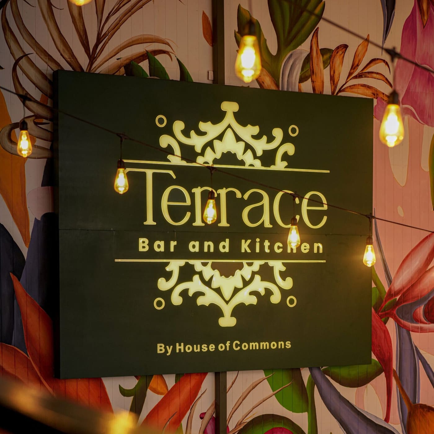 The Terrace Bar and Kitchen sign on a wall of painted tropical leaves
