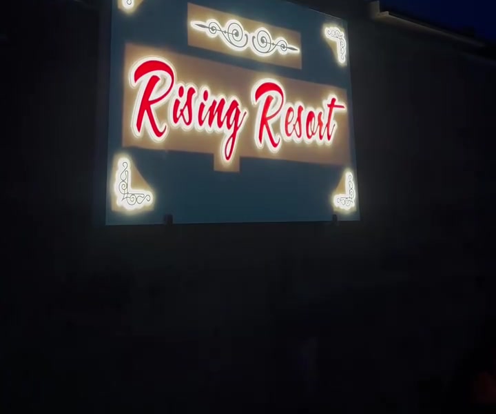 The neon Rising Resort sign at the gate
