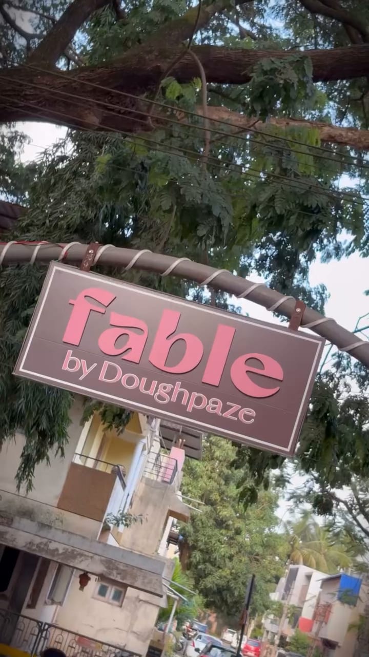 The pink Fable by Doughpaze sign hanging among the trees