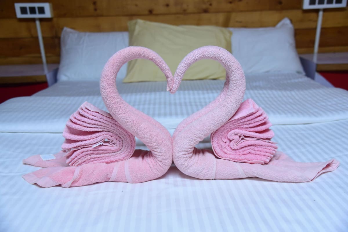Towel swans folded into a heart on the bed
