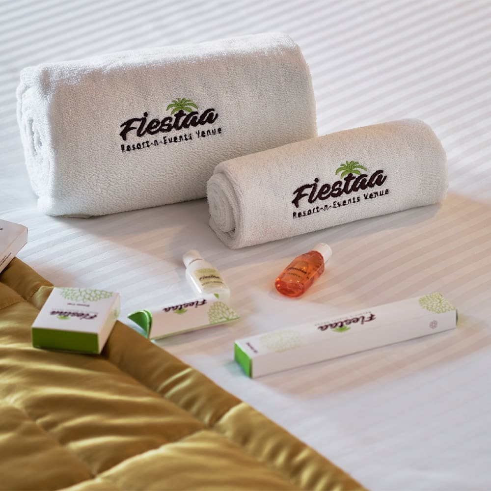 Fiestaa-embroidered towels and amenities on a made bed